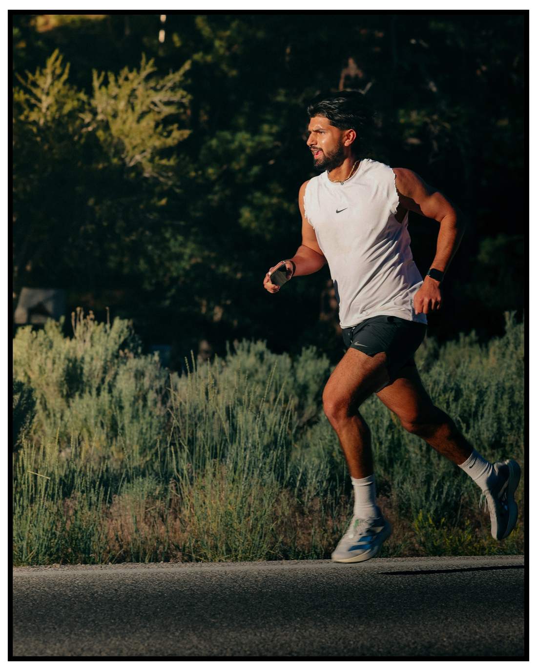 Runner in white tank mid-stride at golden hour