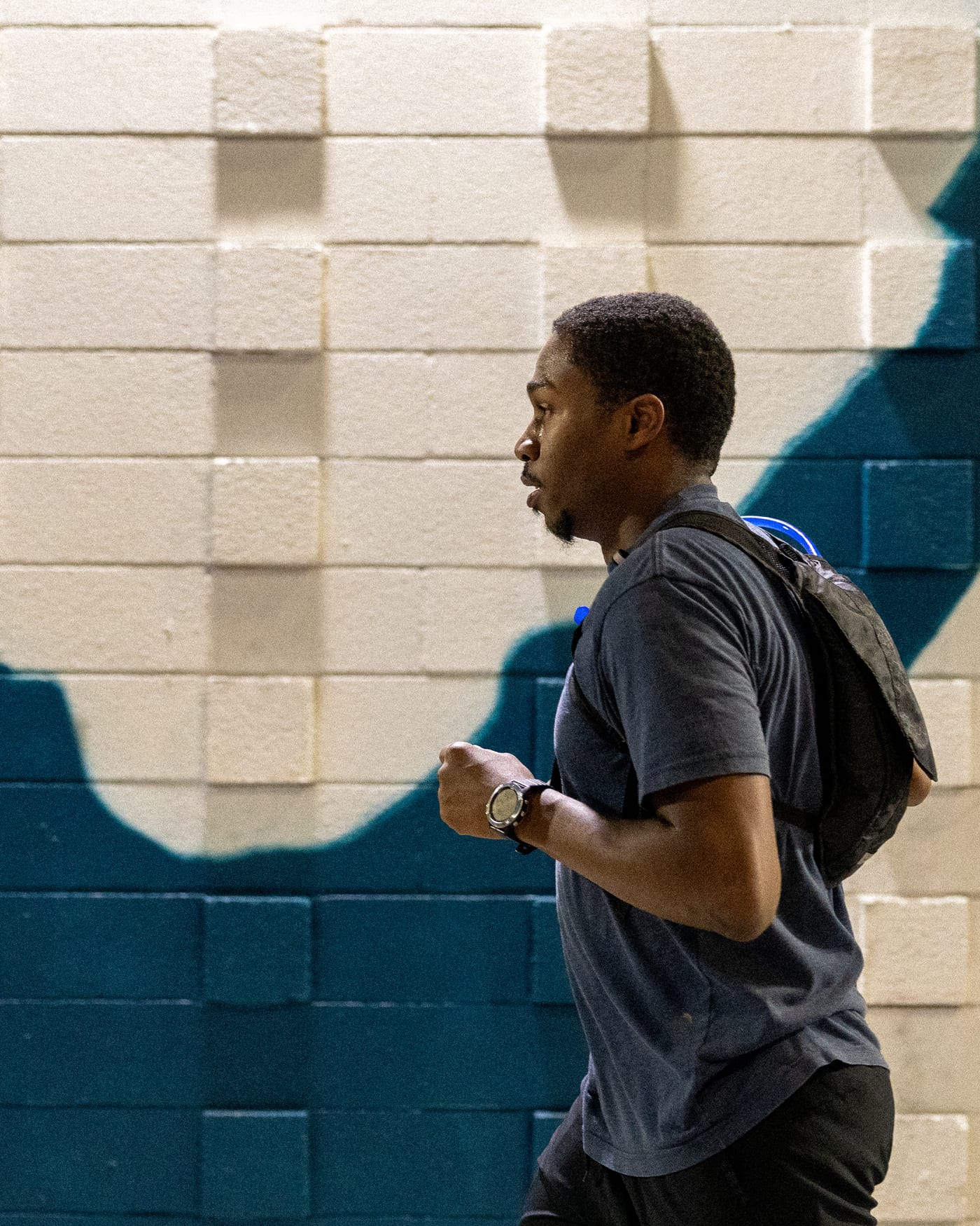 Runner passing a cream and teal brick mural